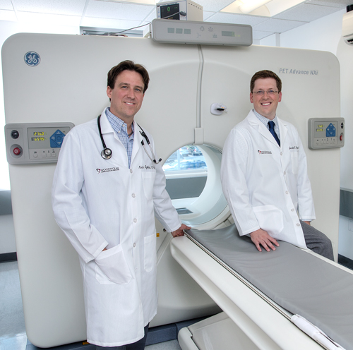 Dr. Martin Engelhardt & Dr. Jonathan Rogers standing in front of a PET scan machine