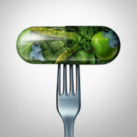 A capsule with fresh fruit and vegetables inside on a fork.