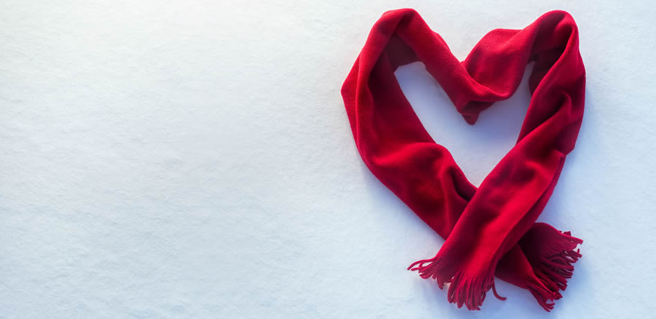 A red scarf in the shape of a heart on the snow.