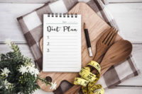 Notepad with Diet Plan list text on chopping board.