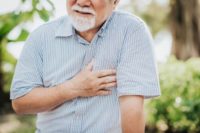 Senior man holding his chest and feeling pain suffering from heart attack.