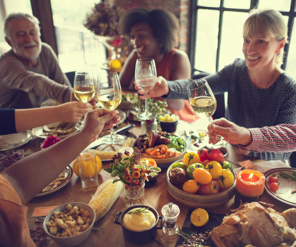 A group of people celebrating a holiday dinner together at home and raising glasses.